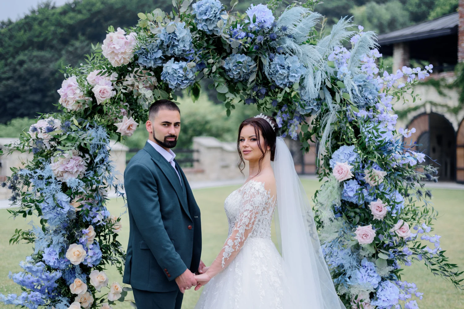 Wedding couple standing in front of a blue hydrangea archway