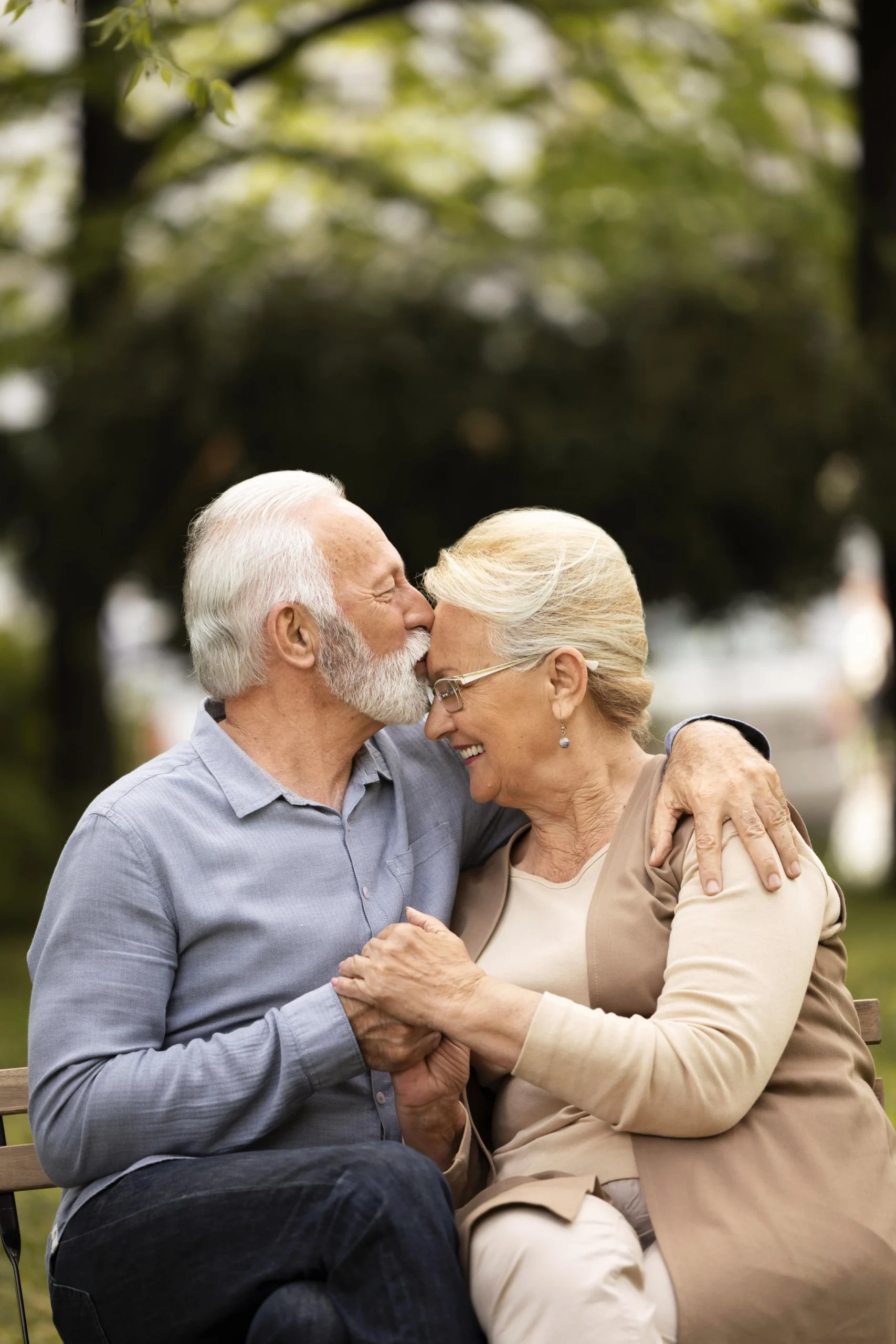 Elderly couple embracing each other on a park bench
