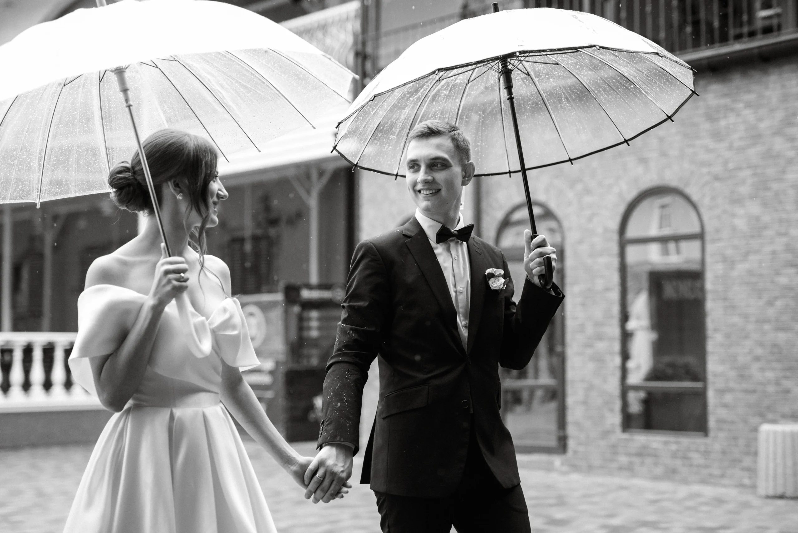Bride and groom walking in the rain with umbrellas